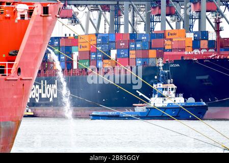 Rotterdam, The Netherlands - June 2019; compressed view of harbour activity in the container terminal, with moored ship in forefront pumping out water Stock Photo