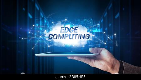 Young business person working on tablet and shows the inscription: EDGE COMPUTING Stock Photo