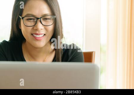 working from home during Coronavirus or Covid-19 outbreak, young woman smiling while conference with team Stock Photo