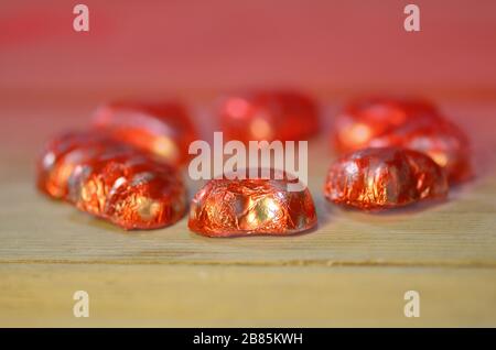 Red chocolate hearts wrapped in red foil for Valentine's Day. Stack of chocolate heart Stock Photo