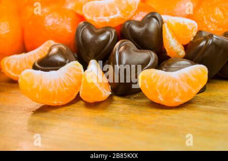 Several cookies in the shape of a heart glazed with chocolate with tangerines Stock Photo