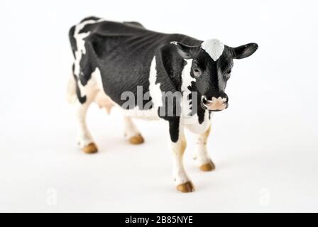Toy cow isolated on a white background. Black and white spotted rubber or plastic cow. Farm animals. Stock Photo