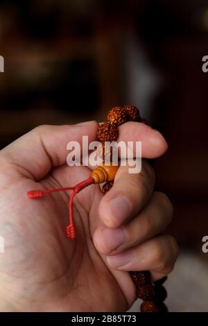 Hand of prayer holding rudraksha beads or rosary Stock Photo