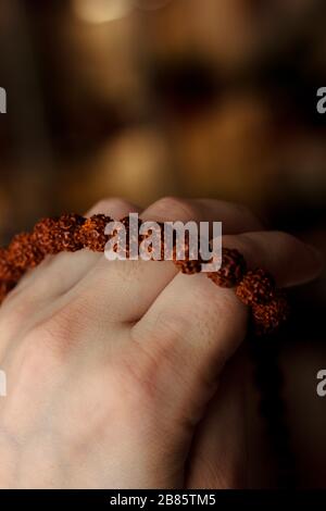 Hand of prayer holding rudraksha beads or rosary Stock Photo