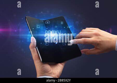 Businessman holding a foldable smartphone with PROXY SERVER inscription, cyber security concept Stock Photo