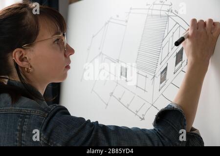 Close-up of a young female architect drawing a sketch for a new famaly home project. Concept of work on technical drawings Stock Photo
