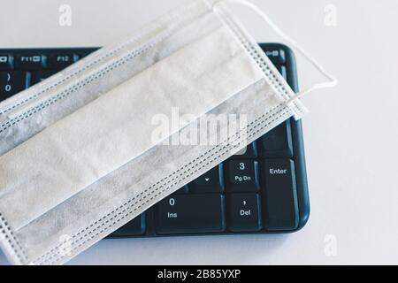 protective mask on the keyboard. Working from home under quarantine and pandemic conditions. Remote work. Stock Photo