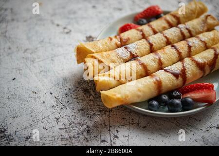 Plate of delicious crepes roll with fresh fruits and chocolate Stock Photo