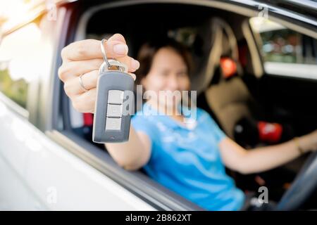 A woman who is glad she has bought a new car. She is proudly holding the car keys, Can reach the achievement point as targeted. Stock Photo