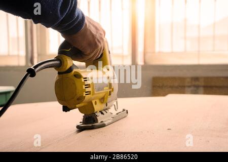 Close-up of a carpenter using a Electric saw to cut a large board of wood. Stock Photo