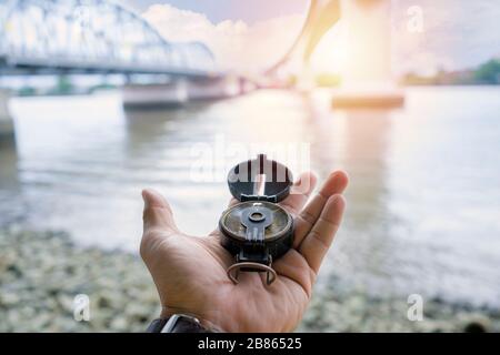 Compass, navigational compass, travel compass, lost compass, The background is a bridge for challenging travel. The large river is like an obstacle. Stock Photo