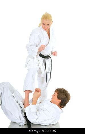 Cute blonde girl and a young cheeky guy karate are engaged in training in a kimono on a white background. Young couple of athletes getting ready for a Stock Photo