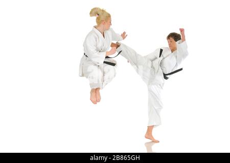 Cute blonde girl and a young cheeky guy karate are engaged in training in a kimono on a white background. Young couple of athletes getting ready for a Stock Photo