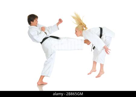 Cute blonde girl and a young cheeky guy karate are engaged in training in a kimono on a white background. Young couple of athletes getting ready for a Stock Photo