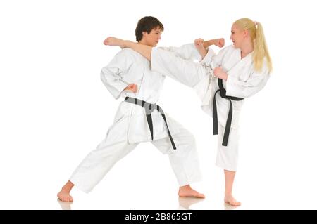 Cute blonde girl and a young cheeky guy karate are engaged in training in a kimono on a white background. Young couple of athletes getting ready for a Stock Photo