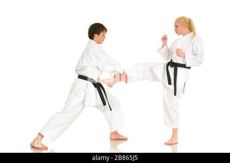 Cute blonde girl and a young cheeky guy karate are engaged in training in a kimono on a white background. Young couple of athletes getting ready for a Stock Photo