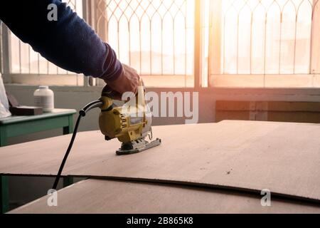 Close-up of a carpenter using a Electric saw to cut a large board of wood. Stock Photo