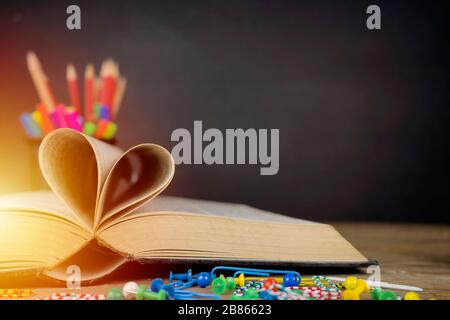 Love story book with open page of literature in heart shape and placed on the table, the background is a blackboard, school study room for national li Stock Photo