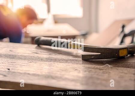 Carpenter building a house and workimg with hammer and wood. The hammer is a front scene object. Stock Photo