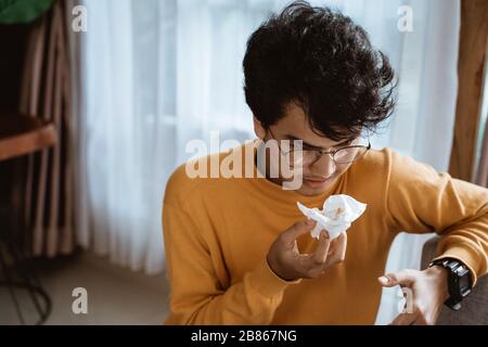 sick man coughing while sitting on a couch Stock Photo