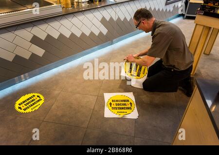 Ardara, County Donegal, Ireland 20th March 2020. A shop manager places stickers on the floor of Centra supermarket reminding customers of 'Social Distancing' due to the Coronavirus, Covid-19, pandemic. People must keep at least 2 metres between each other. Stock Photo