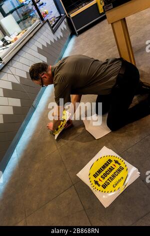 Ardara, County Donegal, Ireland 20th March 2020. A shop manager places stickers on the floor of Centra supermarket reminding customers of 'Social Distancing' due to the Coronavirus, Covid-19, pandemic. People must keep at least 2 metres between each other. Stock Photo