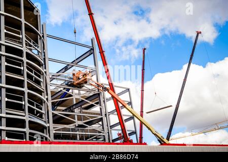 Cranes and cherry pickers in use on the construction of a new building with a steel frame structure. Nottingham, England, UK Stock Photo