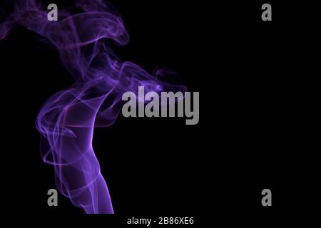 Abstract purple smoke swirling on a black background. Stock Photo