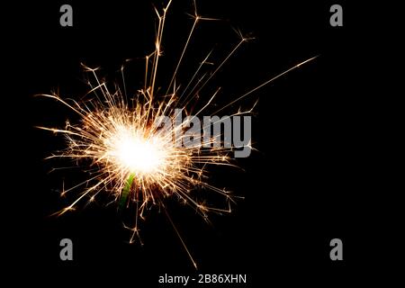 Close-up on a sparkler lit in the dark with copy space on the right. Stock Photo