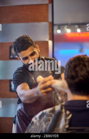 Shaving process of beards in Barbershop. Master makes the client shave his beard with vintage straight razor. Work in the Barber shop, The process of Stock Photo