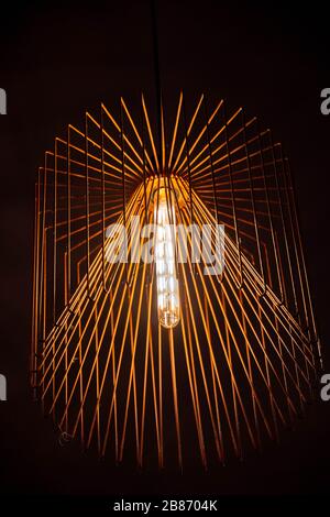 Copper wire carcass chandelier closeup. Modern metal frame lampshade. Lamp with long glass light bulb. Abstract textured background. Geometric lines Stock Photo