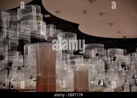 Three dimensional abstract background of curved transparent hangings under ceiling. Futuristic interior decorations. White circle shaped pendant light Stock Photo