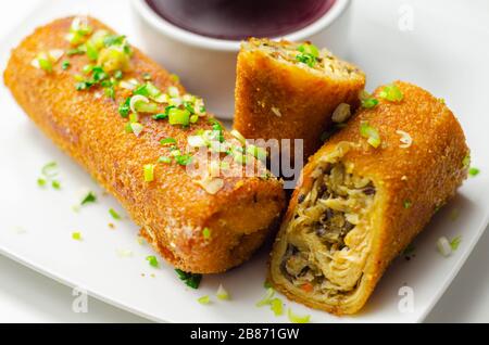 Delicious croquettes with sauerkraut and mushrooms served with hot red borscht, Eastern European cuisine Stock Photo