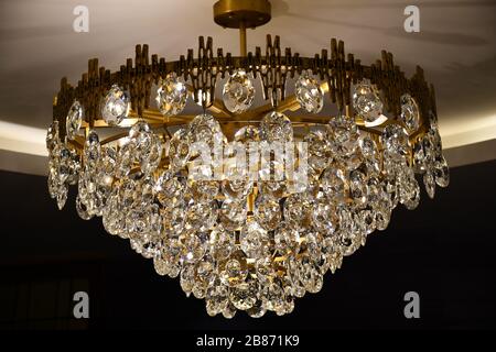 Victorian style antique chandelier with sparkling crystal hangings on dark background. Vintage shiny luster closeup. Luxury interior decoration. Stock Photo