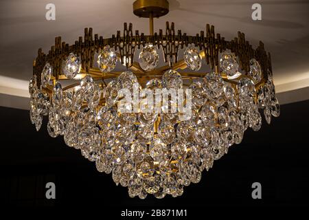Antique chandelier with sparkling crystal hangings on dark background. Vintage shiny luster closeup. Luxury interior decoration. Stock Photo