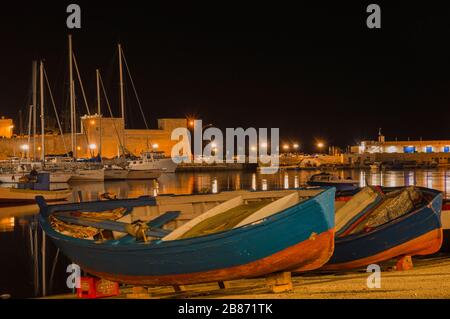 BARI, ITALY - FEBRUARY 16, 2020: rustic wooden boats and yachts in Bari fishing harbor at night Stock Photo