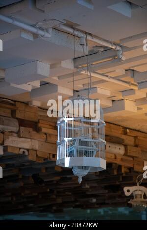 Lampshade made from white painted wooden bird cage. Closeup of birdcage transformed into ceiling lamp with lantern inside. Unusual hanging chandelier Stock Photo