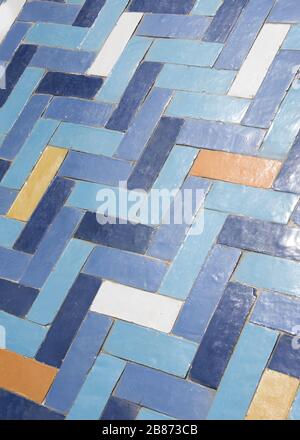 Essaouria, Morocco - September 2017:  Worn  tiled floor in Herringbone pattern, in blue, orange, and white Stock Photo