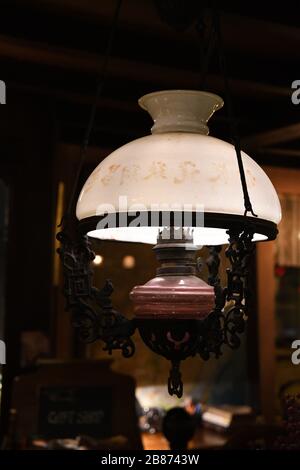 Retro style pendant light in shape of vintage kerosene lamp with matte white glass lampshade globe on dark blurred background. Hanging lighting equipm Stock Photo