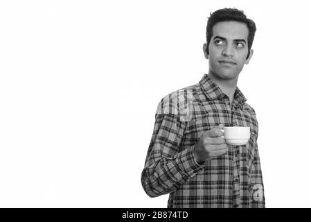 Young Persian man thinking while holding coffee cup Stock Photo