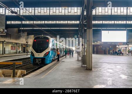 Blue train and commuters on platform on train station in Pretoria, South Africa Stock Photo