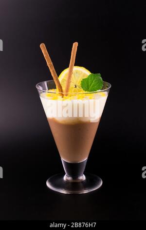 Chocolate and lemon dessert (pudding) is decorated with lemon zest on a black background. Stock Photo