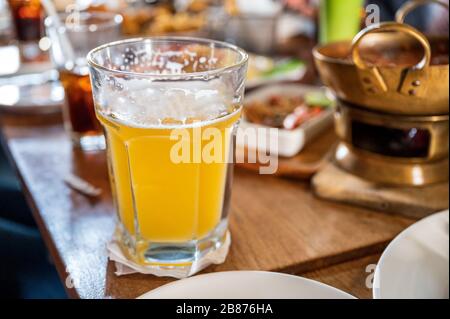 Drinking of Craft beer with foam in big glass on wooden table in restaurant Stock Photo