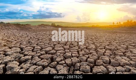 Cracked and dry soil in arid areas landscape with sun and cloud Stock Photo