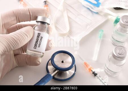 Doctor hand showing vaccine against covid-19 virus on table with medical material. Top view. Horizontal composition.