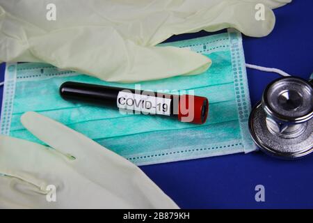 Self protection and test equipment concept in corona crisis: isolated surgical protection face mask and rubber gloves with handwritten word covid-19 Stock Photo