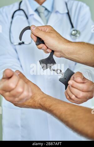 Close-up Of Arrested Doctor's Hand With Handcuffs Stock Photo