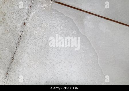 Bubbles soap detergent with scrubbing the bathroom floor dirt wet, Foam white bubble from shampoo washing on Tiled floor top view Stock Photo