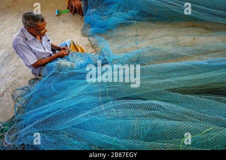Jaffna, Sri Lanka - February 2020: A man repairing nets in the fishing district of Jaffna on February 23, 2020 in Jaffna, Sri Lanka. Stock Photo