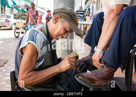 Street shoe shine. Man with a coin in the ear photographed while cleaning the shoes of a client. Stock Photo